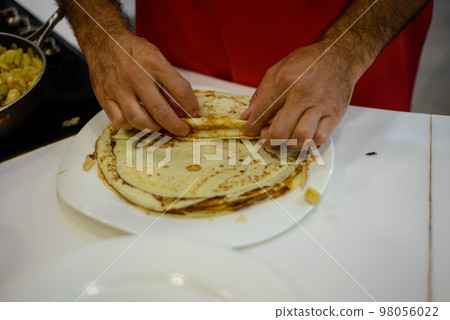 in pancakes wrap the filling on a white plate in the kitchen 98056022