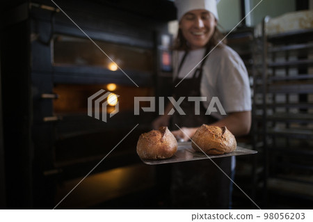 Happy young baker with fresh bread, in bakery. Happy young baker with fresh bread, in bakery. 98056203