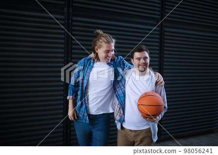 Man with down syndrome playing basketball outdoor with his friend. Concept of friendship and integration people with disability into society. Man with down syndrome playing basketball outdoor with his friend. Concept of friendship and integration people with disability into society. 98056241