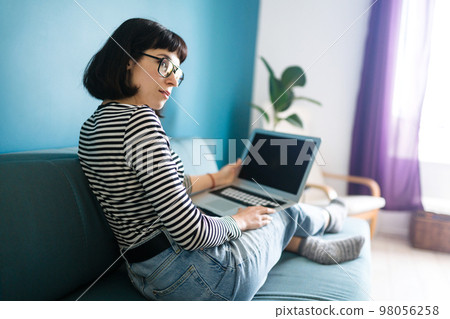 Beautiful woman working on laptop at home. Black screen on laptop. Technology, freelance. 98056258