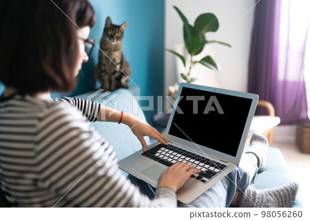Beautiful woman working on laptop at home. Black screen on laptop. Technology, freelance. 98056260