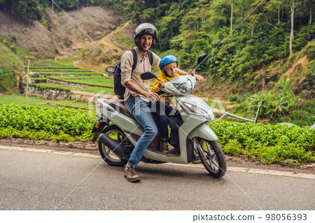 Father and son are traveling on a moped on a tea plantation in Malaysia. Traveling with children concept 98056393