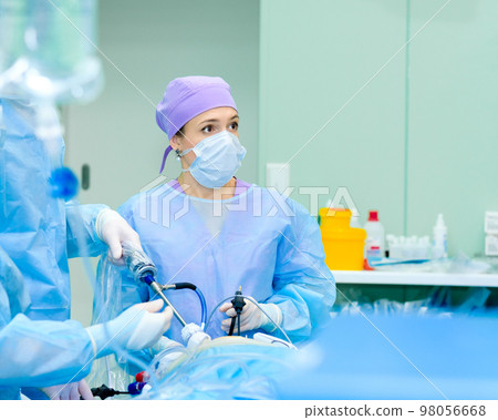 Focused female surgeon performs laparoscopic surgery in the operating room. Focused female surgeon performs laparoscopic surgery in the operating room. 98056668