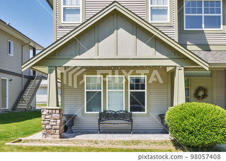 Facade of family house with casted bench at the window beside the entrance 98057408
