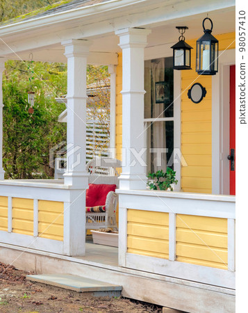 White chair with red pillow on the porch of historical residential house 98057410