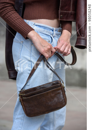 close-up photo of small brown leather bag in a woman hands close-up photo of small brown leather bag in a woman hands 98058248