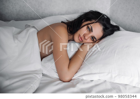 portrait of a girl waking up in bed on pillow in bedroom 98058344
