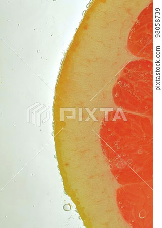 Close-up of juicy grapefruit slice on white background. Slice of red grapefruit in sparkling water on white background, close-up. Vertical macro image Close-up of juicy grapefruit slice on white background. Slice of red grapefruit in sparkling water on white background, close-up. Vertical macro image 98058739