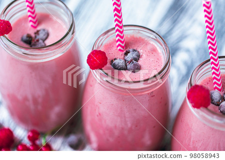 Closeup top view of three milkshakes in glasses jars made from raspberry, blueberries, currant 98058943