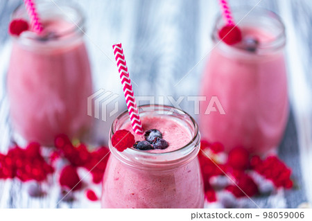Three yogurt smoothie with cranberry, raspberry, blueberry on wood table in jars. Selective focus Three yogurt smoothie with cranberry, raspberry, blueberry on wood table in jars. Selective focus 98059006