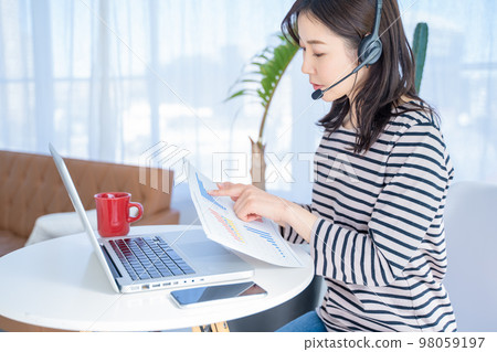 A woman who video chats while showing materials at home work 98059197