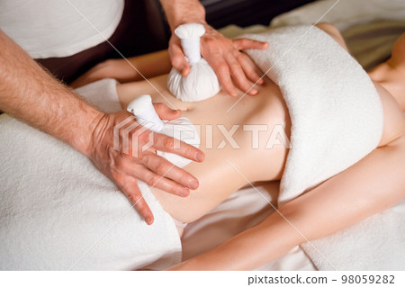 Woman having an abdomen massage with with aromatic herbal bags Woman having an abdomen massage with with aromatic herbal bags 98059282