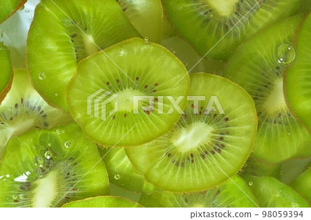 Kiwi fruit close-up in liquid with bubbles. Slices of gren ripe kiwi fruit in water. Close-up fresh slices of green kiwi fruit on white background. Top view, flat design Kiwi fruit close-up in liquid with bubbles. Slices of gren ripe kiwi fruit in water. Close-up fresh slices of green kiwi fruit on white background. Top view, flat design 98059394