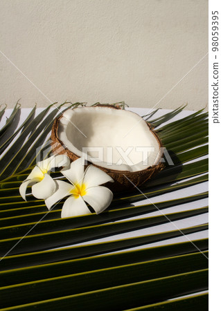 Tropical fruit concept, Halves of fresh coconut with leaves and plumeria flower on white background 98059395