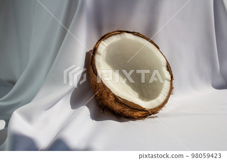 Tropical fruit concept, Halves of fresh white coconut on white fabric background 98059423