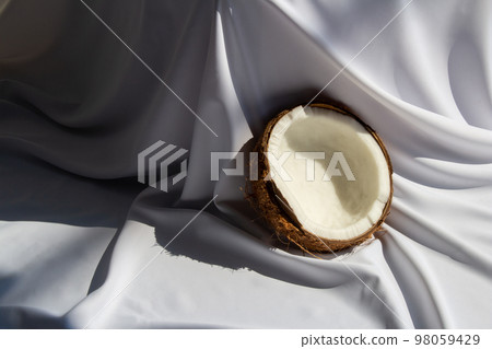 Tropical fruit concept, Halves of fresh white coconut on white fabric background 98059429