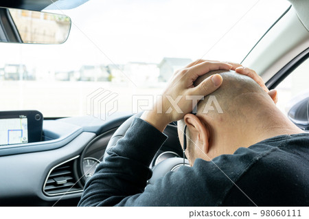 Man depressed in the driver's seat of a car 98060111