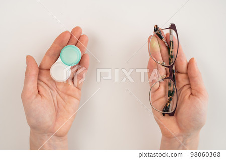 A woman makes a choice between lenses and glasses. Weighs the decision and chooses lenses. 98060368
