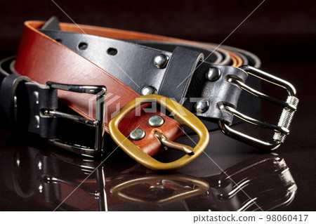 A group of multi-colored leather belts on a black background. A group of multi-colored leather belts on a black background. 98060417