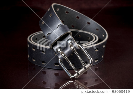Black leather belt on a dark background. Leather products. Black leather belt on a dark background. Leather products. 98060419