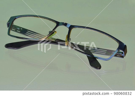 Reflection of eyeglasses. Blue eyeglasses, close-up. Eye glasses. Old style eyeglasses. Glasses with transparent lenses. Vintage Glasses on reflected background. Close up of worn out eyeglasses Reflection of eyeglasses. Blue eyeglasses, close-up. Eye glasses. Old style eyeglasses. Glasses with transparent lenses. Vintage Glasses on reflected background. Close up of worn out eyeglasses 98060832