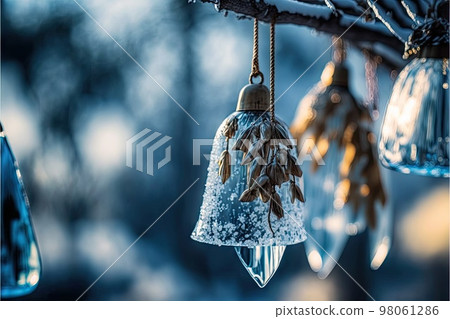 Crystal bells hanging on bare tree branch with winter nature in background 98061286
