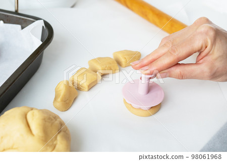 The process of making cookies with shapes in the form of flowers, a rolling pin and a tray, the concept of cooking, baking at home. The process of making cookies with shapes in the form of flowers, a rolling pin and a tray, the concept of cooking, baking at home. 98061968