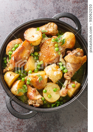 Homemade Baked Chicken Vesuvio with Peas and Potatoes closeup on the black pan. Vertical top view Homemade Baked Chicken Vesuvio with Peas and Potatoes closeup on the black pan. Vertical top view 98062050