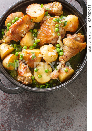 Chicken Vesuvio is a classic Italian-American dish for baked chicken with potatoes, peas, white wine sauce, and seasonings close-up in a frying pan. Vertical top view Chicken Vesuvio is a classic Italian-American dish for baked chicken with potatoes, peas, white wine sauce, and seasonings close-up in a frying pan. Vertical top view 98062051