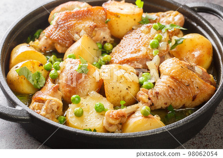 Italian American cuisine Chicken Vesuvio a skillet with potatoes, garlic, green peas closeup on the black pan. Horizontal Italian American cuisine Chicken Vesuvio a skillet with potatoes, garlic, green peas closeup on the black pan. Horizontal 98062054