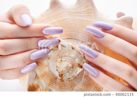 Hand with long violet manicured nails and seashell Hand with long violet manicured nails and seashell 98062135