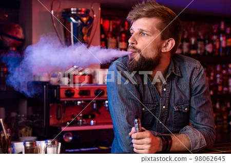 Vape. Vaping man in a cloud of vapor. Photo is taken in a vape bar. 98062645