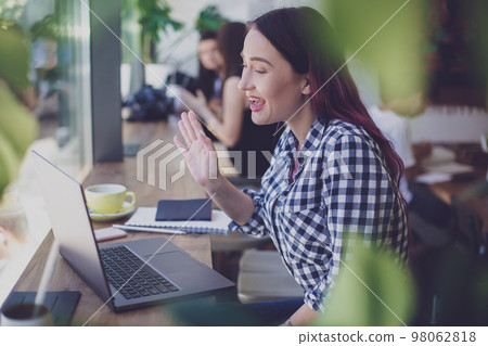 Side view of young businesswoman sitting at table in coffee shop Side view of young businesswoman sitting at table in coffee shop 98062818