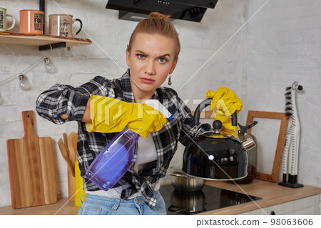 Domestic service and housekeeping concept, happy blonde lady cleaning kitchen kettle. Domestic service and housekeeping concept, happy blonde lady cleaning kitchen kettle. 98063606