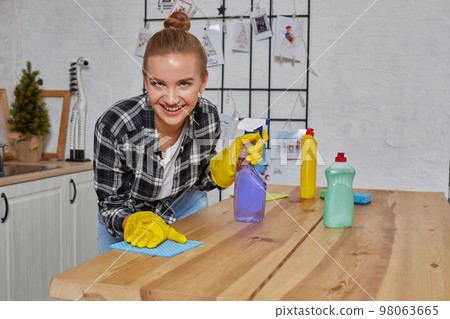 Young woman or housewife in rubber gloves wiping table with microfiber cloth at home kitchen. Young woman or housewife in rubber gloves wiping table with microfiber cloth at home kitchen. 98063665
