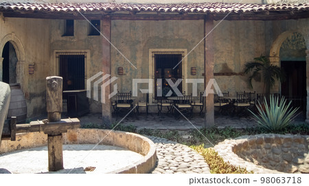 mechanical distillery wheel, roof tiles, tables and chairs in the background, old distillery, mexico 98063718