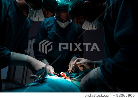 Surgical team performing surgery to patient in sterile operating room. Surgical team performing surgery to patient in sterile operating room. 98063906