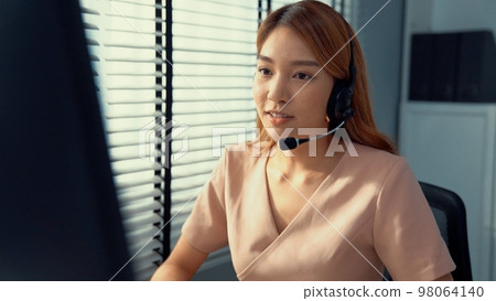 Competent female operator working on computer and while talking with clients. Competent female operator working on computer and while talking with clients. 98064140