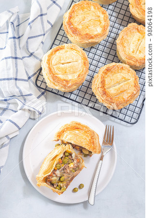 Sliced beef pot pie on plate, pies on cooling rack, vertical, top view Sliced beef pot pie on plate, pies on cooling rack, vertical, top view 98064198