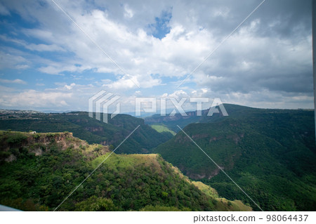 ravine trees and vegetation, view of several mountains at different depths, blue sky and few clouds, mexico ravine trees and vegetation, view of several mountains at different depths, blue sky and few clouds, mexico 98064437