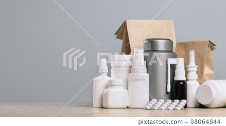 Online pharmacy. prescription drugs and over the counter medication ready for delivery to customers. Pills and spray white mockup containers and buff paper bags on table. Drugstore shopping 98064844