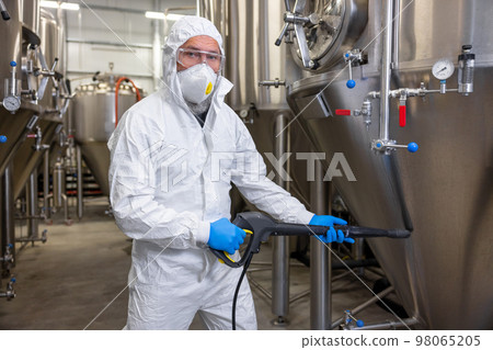 Factory worker disinfecting the beer production equipment Factory worker disinfecting the beer production equipment 98065205