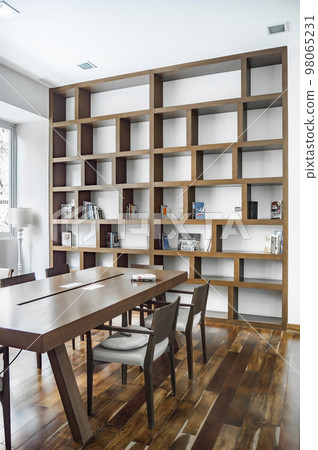 elegant dining room with a bookcase in the background, both the dining table and the natural wood bookcase. 98065231
