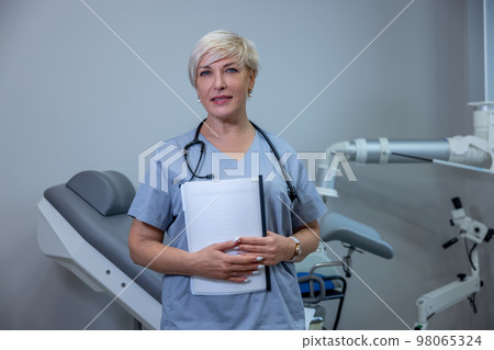 Female doctor in blue scrubs sitting in the medical office 98065324