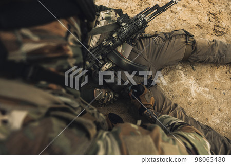 Wounded man lying on a ground, other soldiesr next to him Wounded man lying on a ground, other soldiesr next to him 98065480