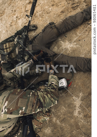 Wounded man lying on a ground, other soldiesr next to him Wounded man lying on a ground, other soldiesr next to him 98065481