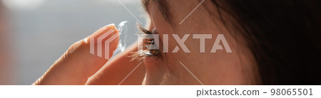 Close-up portrait caucasian woman putting on a contact lens. Widescreen. Close-up portrait caucasian woman putting on a contact lens. Widescreen. 98065501