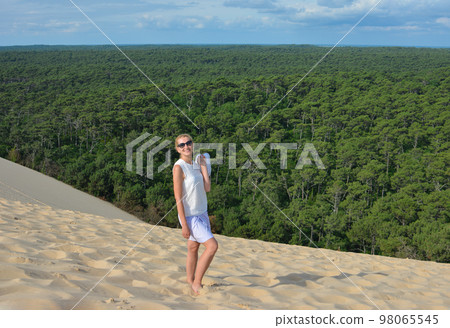 A girl in the background of a coniferous forest at Pyla dune, the largest sand dune in Europe 98065545