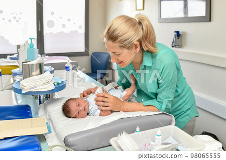 A nurse take cares of a newborn baby in the maternity hospital. First bath. A nurse take cares of a newborn baby in the maternity hospital. First bath. 98065555