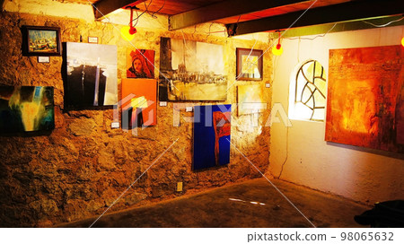 small room with display of student artwork, with wiring and cracked walls, metal beams and wood staves small room with display of student artwork, with wiring and cracked walls, metal beams and wood staves 98065632